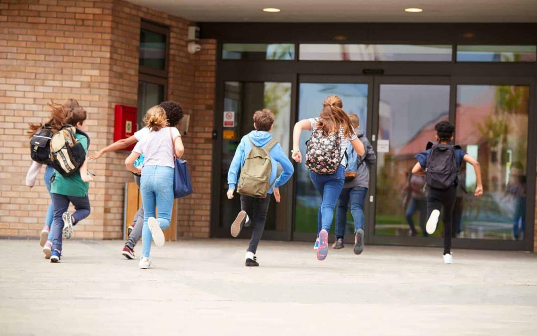 Kids running toward a glass door building