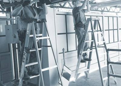 Two people standing on ladders operating cables