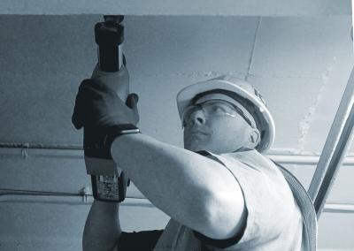 Man with a hat and glasses operating a drilling machine